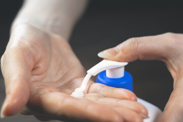 Woman is squeezing white moisturizing cream from a jar on her hand. Cosmetology, skin care, beauty treatment. Close up view.