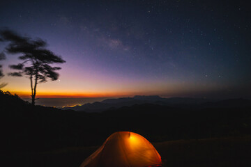 nature traveling with orange camping tent on mountain with milky way background