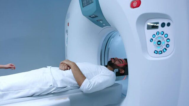 Doctor processing positron emission tomography procedure in clinic. Magnetic resonance imaging scanner x-ray machine imaging body, lights up infrared rays and passes through circle.