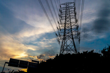 High voltage pole silhouette on sunset sky background.