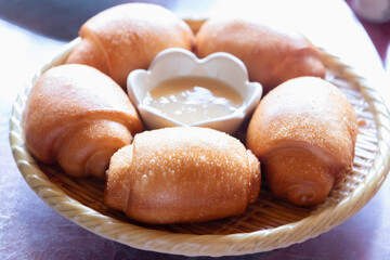 Golden fried Mantou or Chinese fried bun in a basket with sweet condensed milk on the table.