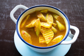 Yellow curry with fish, bamboo shoot and green taro (aaw dip) thai southern style food on wooden table.
