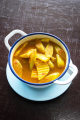 Yellow curry with fish, bamboo shoot and green taro (aaw dip) thai southern style food on wooden table.