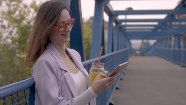 Business woman drinking juice and using phone at the same time, city break