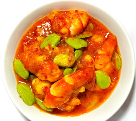 Selective focus. Chili prawns or Sambal Udang with petai or pete in white plate on white background. Indonesia cuisine food. 
