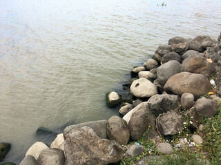 Large rocks piled up at the side of the lake, which are arranged to form a breakwater