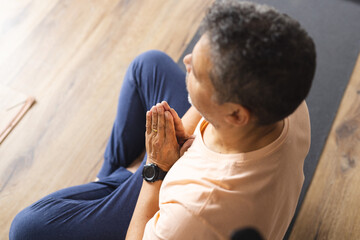 Biracial senior man with graying hair practices yoga in a serene indoor setting
