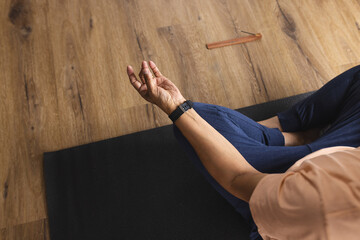 Biracial senior man meditates on a yoga mat, his hand in a mudra gesture