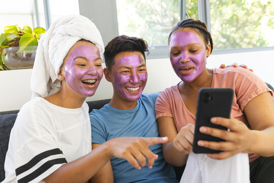 Three friends enjoy a spa day at home, laughing and taking selfies