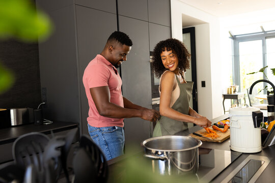 Biracial couple cooking together in a modern kitchen at home