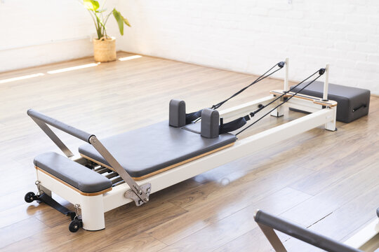 A Pilates reformer machine is ready for a workout in a bright studio