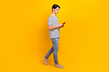 Full length photo of intelligent guy wear t-shirt look at smartphone read email walk to empty space...