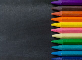 Colorful crayons on the blackboard. Back to school background. Copy space for text.