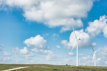 Sustainable energy windmills in a lush field under a cloudy blue sky for environmental conservation concepts