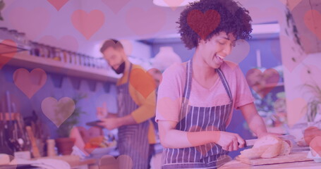 Image of hearts over happy diverse couple preparing meal
