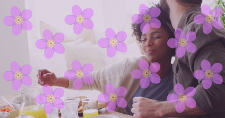 Image of flowers over happy diverse couple eating together