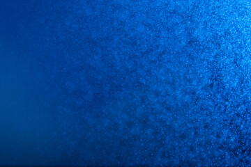 abstract blue sparkling background with a ray of light and many small splashes