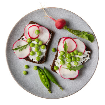 Open sandwich with cream cheese, green pea , radish and arugula on gray plate isolated on white. Vegetarian sandwich on rye bread with vegetables. Top view.