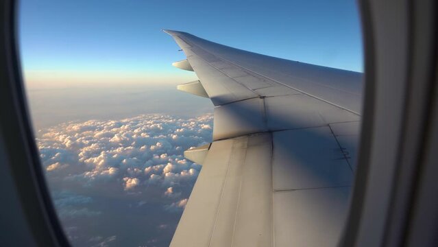 Airplane flight. Wing of an airplane flying above the clouds with sunset sky. View from the window of the plane.  Wing view from window seat.