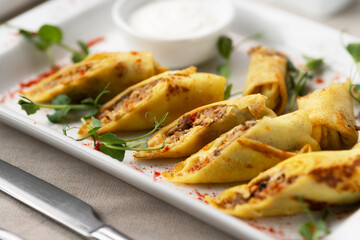 Thin pancakes with fillings. Fried thin pancakes with chicken meat and sauce on table