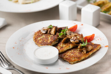 Potato pancakes with mushrooms. Potatoes pancakes on white plate with sour cream. Copy space