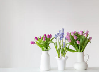 spring flowers in white vases in white interior