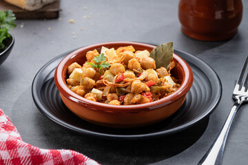 Ropa vieja, typical Canarian dish of chickpeas stew with chicken and potatoes in a earthenware casserole.
