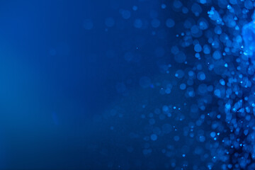 abstract blue sparkling background with many large and medium and a cloud of tiny glare from splashes and light gradient