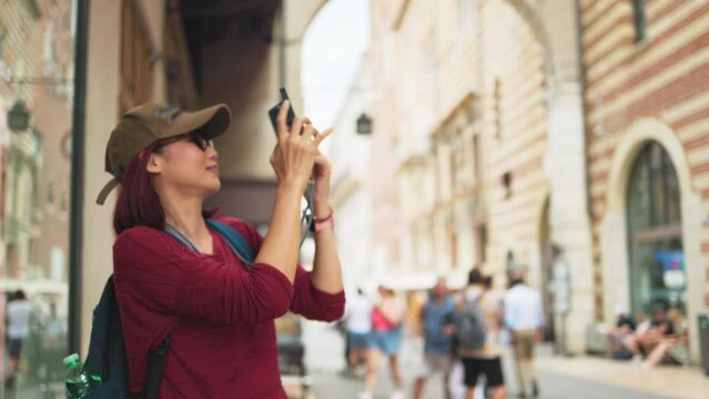Happy young Asian tourist woman selfie by mobile smartphone, female traveller taking photo, recording vlog on holiday vacation trip at italy.