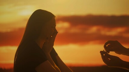 Silhouette of a woman accepting an engagement proposal at sunset