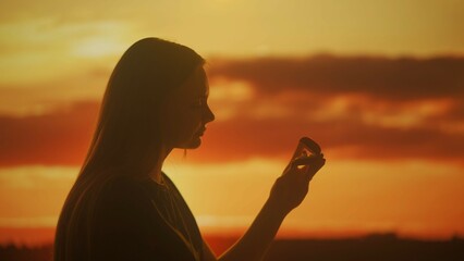 Silhouette of a woman with a box with a jewelry ring in her hands at sunset