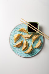 Gyoza dumpling with pork on blue ceramic and soy sauce top view