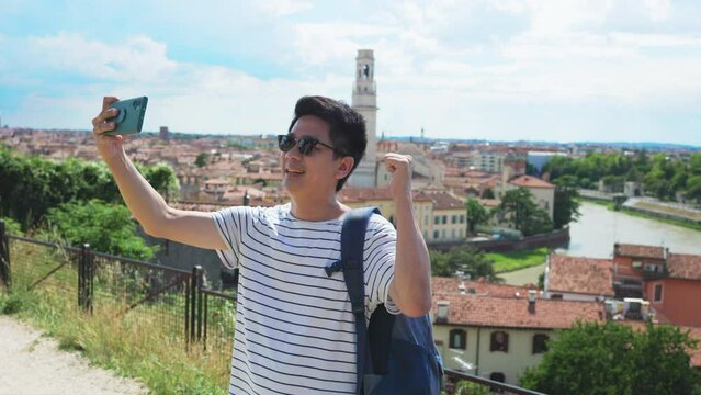 Happy young Asian tourist man selfie by mobile smartphone, Male traveller taking photo, recording vlog on holiday vacation trip at italy.