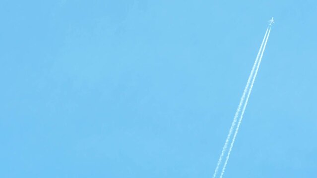 A passenger plane flies against a background of a blue sky without clouds.A long white trail remains behind the plane and gradually dissolves.Travel themed background with empty space for information