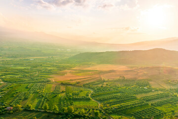 scenic rustic landscape with green hills and farms in a mountain valley during colorful cloudy sunset