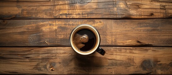A cup of black coffee sits on a textured wooden table, exuding warmth and comfort in a simple setting.