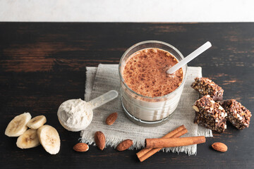 Glass with protein drink, healthy milkshake smoothie on wooden board with bananas, protein powder...