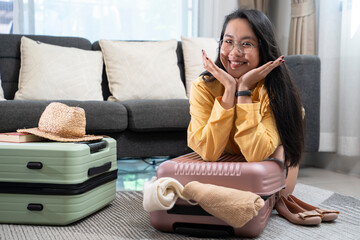 Fron view of a young woman sitting on the ground as she packs her suitcase for her vacation trip.
