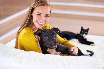 Woman, pets and relax on sofa in portrait, smile for dog and cat love with bonding at home. Happy, positive and trust with foster or adoption, cuddle puppy in living room and domestic animal care