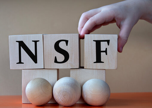 A child's hand places a large cube next to other cubes. NSF acronym concept