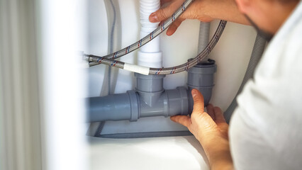 Close up plumber hands repair plumbing pipes in kitchen sink. Removing blockage clog in drain pipe. Replacement of plumbing pipes - obrazy, fototapety, plakaty