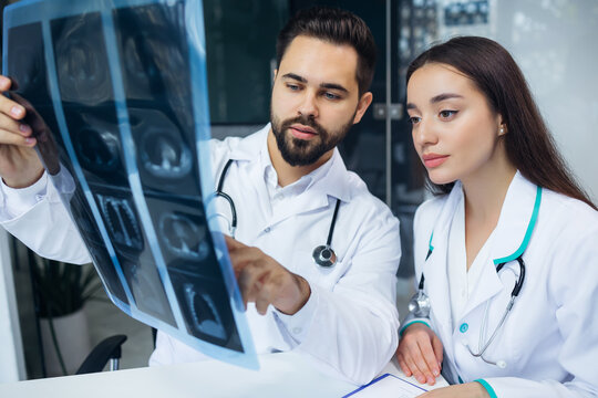 Closeup portrait of intellectual healthcare professionals with white labcoat, looking at x-ray radiographic image, ct scan, mri. Radiology department
