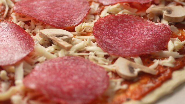 Raw Mushrooms with Salami and Cheese on Pizza Dough. Close-up, shallow dof. - Powered by Adobe