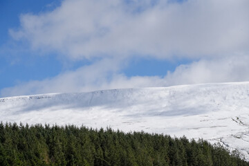 Welsh mountain winter landscape. Snow on the top of the mountains above Storey Arms in the Brecon Beacons.  Icy conditions but the sun is shining and has melted the snow of the foothills.