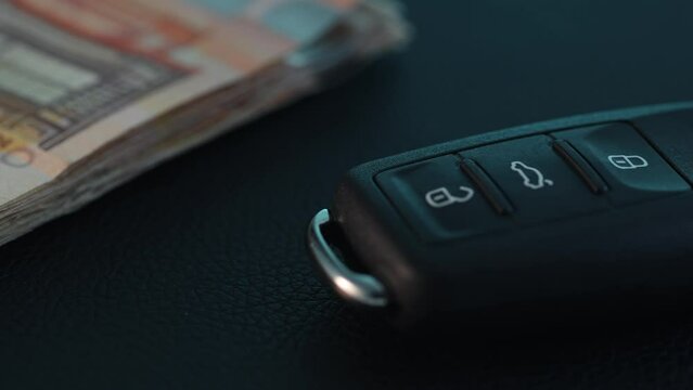 Car key next to a stack of money. Close-up, shallow dof.