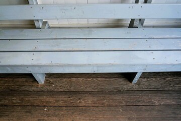 Breite graue Holzbank auf braunem Holzfußboden auf Terrasse am Nachmittag im Frühling
