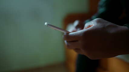 Close-up hand typing on cellphone device. One young black man's hands holding phone engaged in modern communication