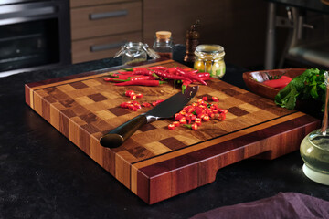 Cut pieces of hot red pepper on beautiful wooden boards on a home kitchen background.