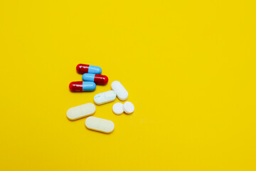 photo of medicine capsules and tablets isolated on yellow background