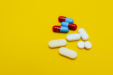 photo of medicine capsules and tablets isolated on yellow background